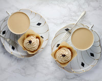 Coffee cupcake with icing with a cup of coffee on the side, all on a pretty plate.