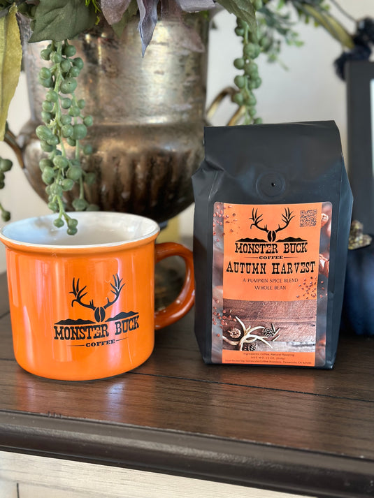 Monster Buck Coffee Autumn Harvest, a pumpkin spice blend. An iridescent orange Monster Buck Coffee camping mug sits next to the coffee. This is a seasonal blend and will be gone after Thanksgiving.