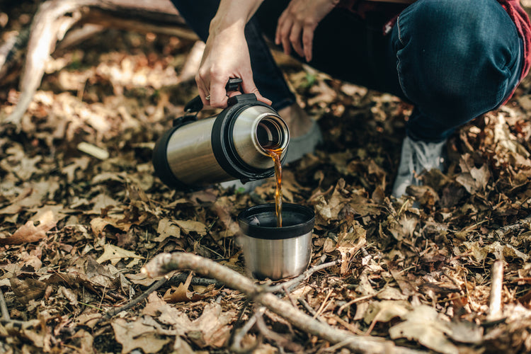 Aa thermos of coffee being poured into the thermos cup by a camper.